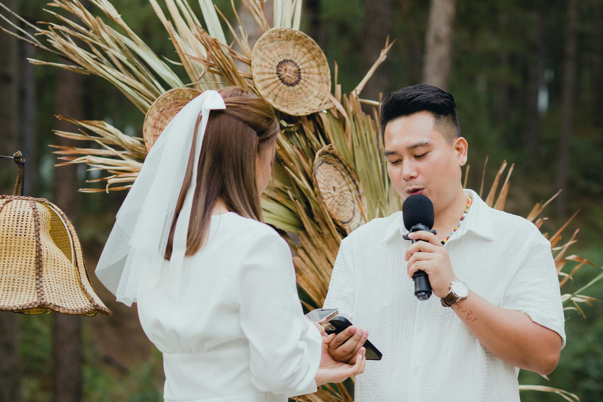 A couple exchanges vows outdoors, surrounded by nature with rustic decor.
